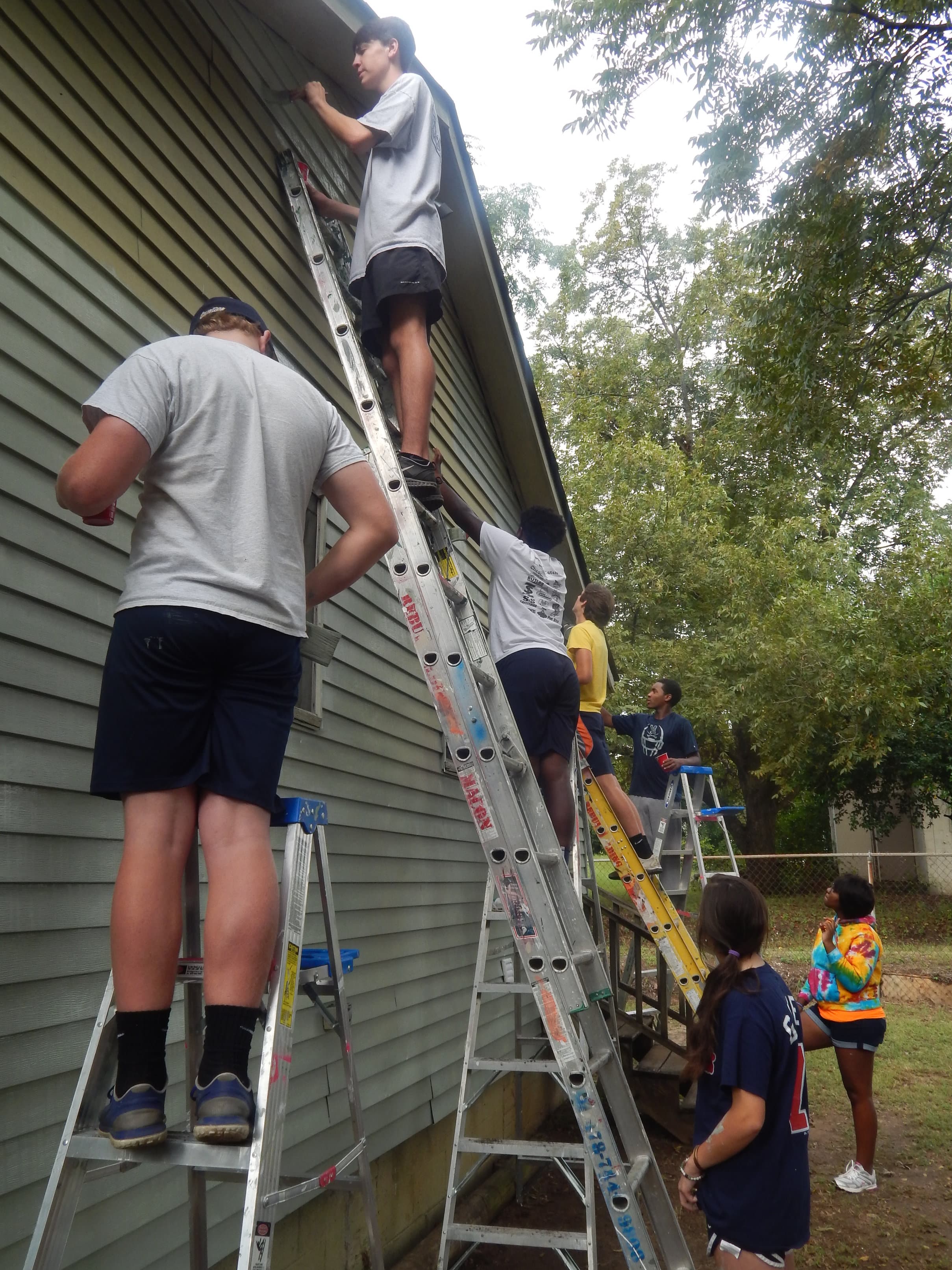 Students painting a home through the school's Mercy In Action program and in partnership with Rebuilding Macon.